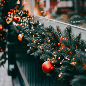 Guirlande de sapin ornée de boules rouges et de petites lumières, placée sur une rambarde pour une touche festive en extérieur ou en intérieur. guirlande-sapin-noel-rambarde