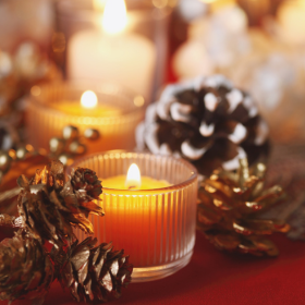 Ambiance cosy de Noël avec bougies allumées et pommes de pin dorées, parfaite pour une décoration chaleureuse et naturelle. ambiance-noel-bougies-pommes-pin