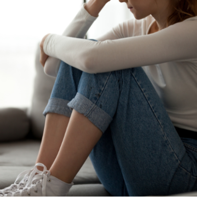 personne assise, les bras autour des jambes, exprimant la solitude et la tristesse dans un cadre intérieur personne-assise-solitude-tristesse