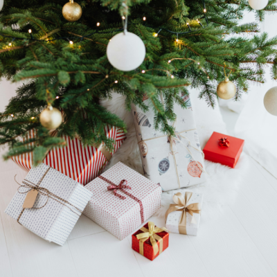 Cadeaux joliment emballés disposés au pied d’un sapin de Noël décoré, créant une atmosphère magique et festive. cadeaux-noel-au-pied-du-sapin