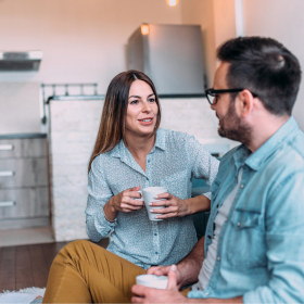 Moment chaleureux entre un couple discutant autour d’une boisson chaude dans une cuisine cosy, ambiance cocooning et conviviale. moment-couple-detente-cocooning