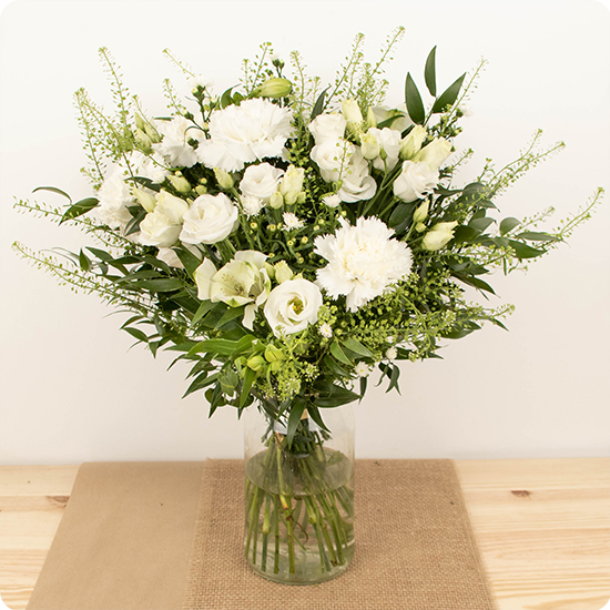 Une création florale élégante et intemporelle composée de délicates fleurs blanches et de feuillages variés.