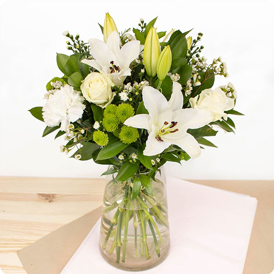 Ce bouquet est composé de majestueux lys, de superbes roses blanches et de fleurs de saison