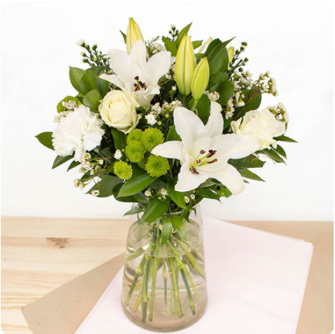 Ce bouquet est composé de majestueux lys, de superbes roses blanches et de fleurs de saison
