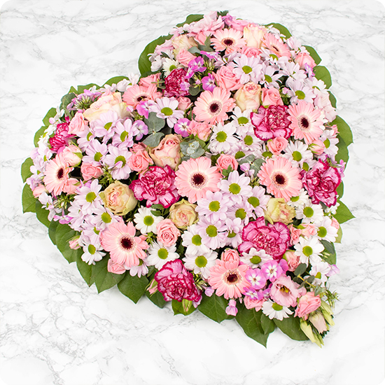 Elégant cœur de fleurs pour deuil composé de chrysanthèmes et d'autres fleurs de saison dans un camaïeu de roses. Pleine de douceur et d'amour,