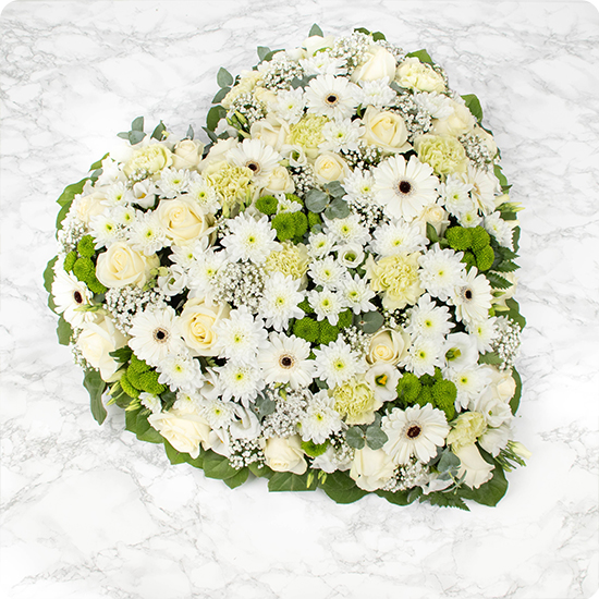 Cœur de fleurs délicat et raffiné composé de fleurs blanches, symbole de paix et de pureté, offrant ainsi une touche de sérénité dans des moments difficiles.