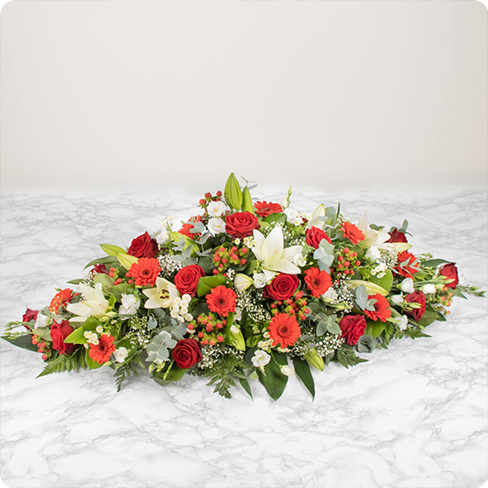 Raquette de fleurs composée de majestueuses roses rouges et d'élégants lys blancs, deux fleurs qui expriment à la fois la pureté et l'amour. Grâce à la symbolique de ses fleurs