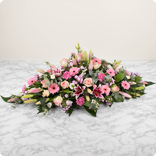 Élégante raquette de fleurs pour deuil aux tons roses. Composée de beaux lys, de majestueuses roses et de délicates fleurs de saison