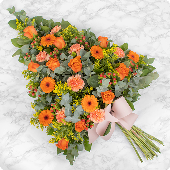 Cette gerbe de fleurs pour deuil associe d'élégantes fleurs aux tons orangés et un délicat feuillage pour créer un ensemble coloré et grâcieux. 
