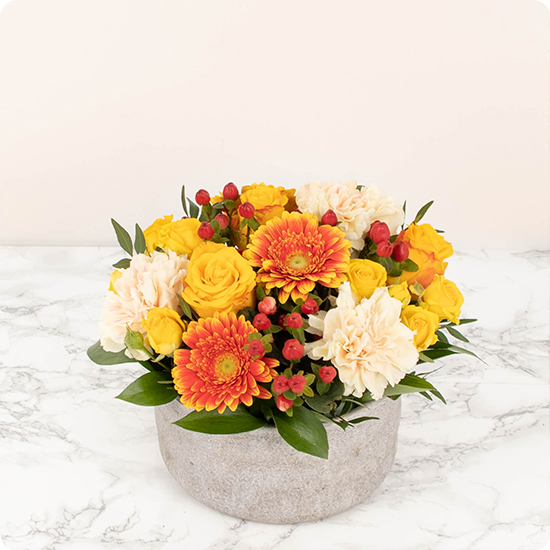 Arrangement de fleurs pour deuil composé d'élégantes roses et de fleurs de saison dans des teintes orangées
